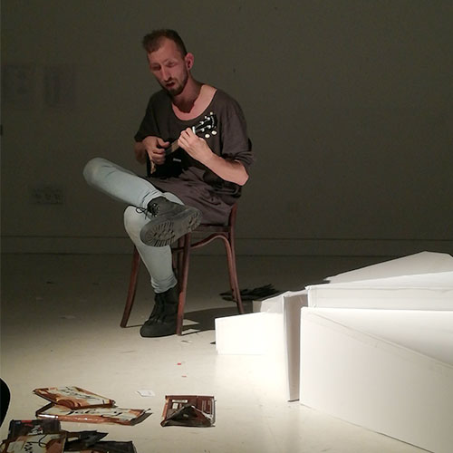 The protagonist sitting on a stool playing the ukulele